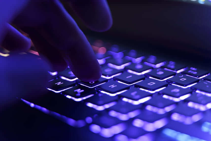 transição de carreira: pessoa digitando em teclado iluminado com luz levemente roxa